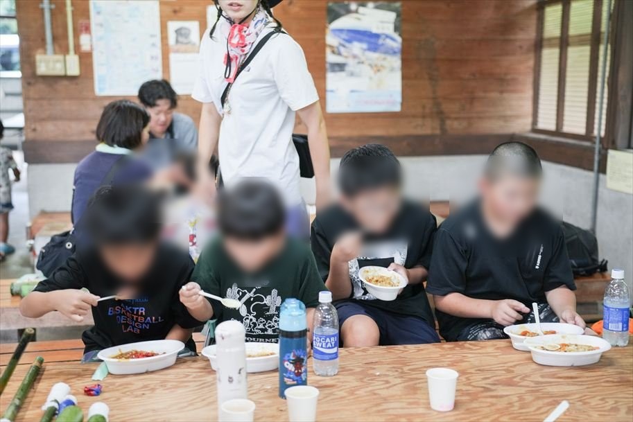長机に並んでカレーを食べる子どもたち