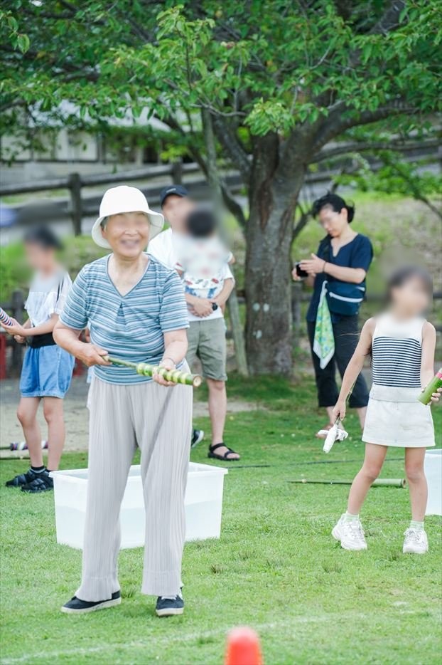竹の水鉄砲を構えて楽しむ年配の参加者